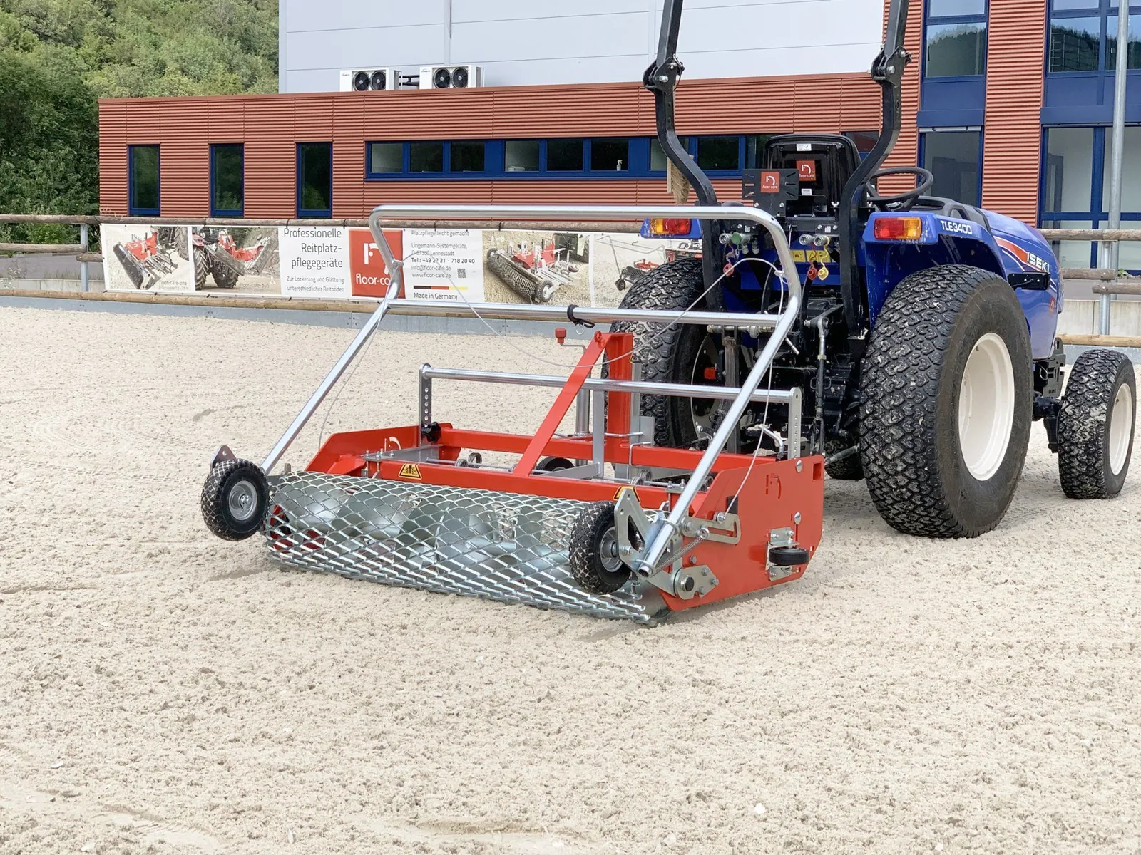 Floor-Care AHK 145/200 met beugel achter een compacte trekker in een zandbak