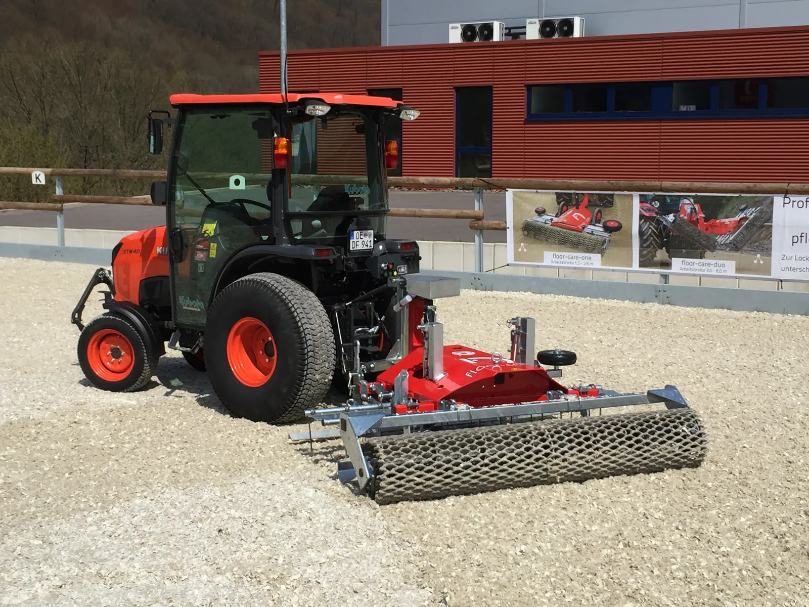 Floor-Care ONE achter een rode Kubota-trekker bij een bedrijfspand
