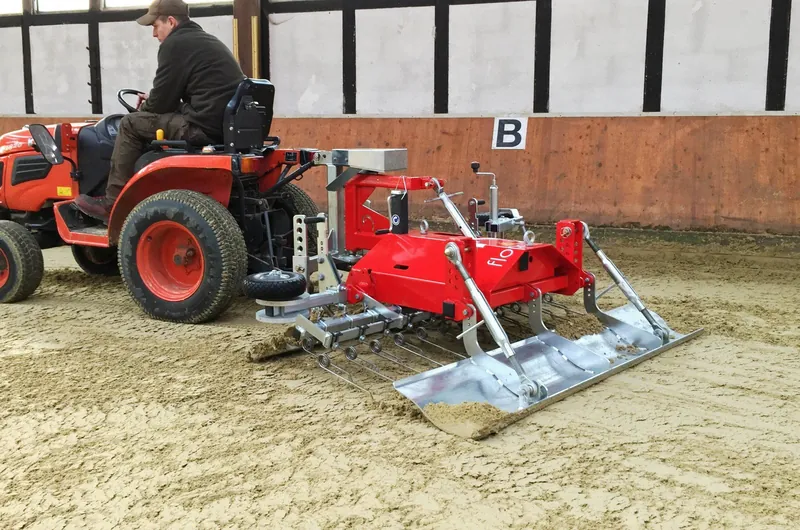 Floor-Care TRAIL manegevlakker achter een trekker in een overdekte binnenbak